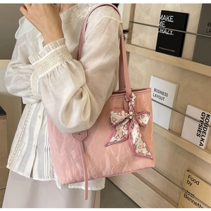 Detail of light pink tote bag with pleated texture and decorative silk scarf on the strap