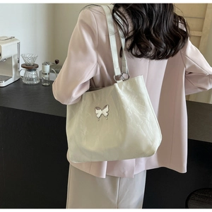 Detail of silver butterfly ornament and pleated texture on cream white tote bag