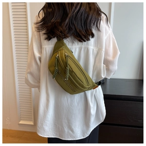 Close-up of olive green crossbody waist bag with embroidery and woven zipper pulls