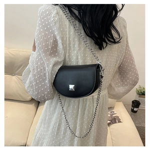 Detailed view of black PU saddle bag with silver metal studs and chain strap