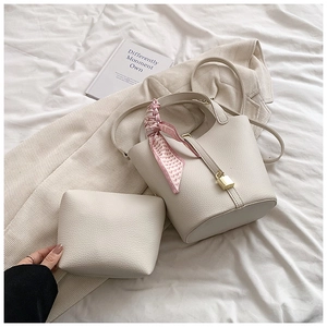 Detail of off-white lychee leather bucket bag with pink heart silk scarf and gold lock