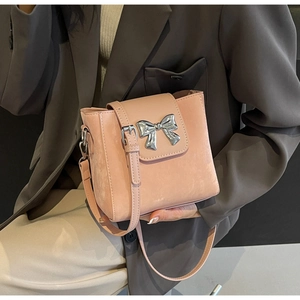 Detail of light pink bucket bag with silver metal bow buckle and matte leather texture