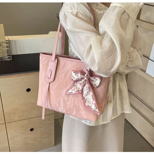 Detail of pink pleated tote bag with stylish decorative ribbon bow and soft texture