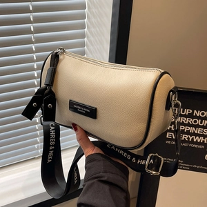 Elegant cream cylinder shoulder bag with wide black strap and litchi grain texture
