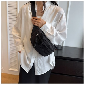Detail of black nylon crossbody chest bag with embossed lettering and woven zip pullers