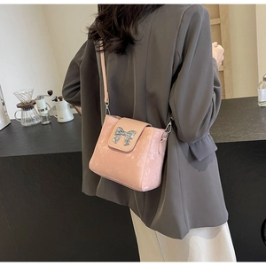 Close-up of pink bucket bag with silver bow buckle worn by model in a cafe