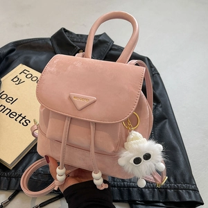 Pink mini backpack with drawstring closure, featuring a plush monster charm and top handle