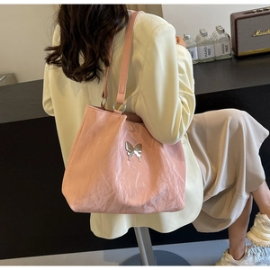 Detailed view of pink tote bag with metallic butterfly accent and glossy leather texture