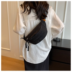 Detail of black nylon chest bag with embossed lettering and braided zipper pull