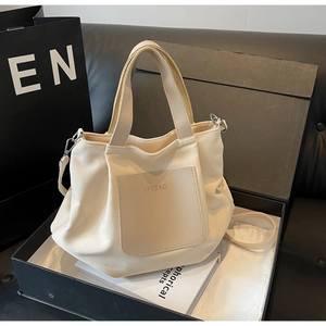 Détail du sac fourre-tout en nylon crème avec poche en cuir et logo dans un emballage chic