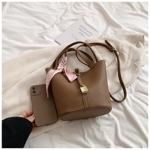 Close-up of brown litchi pattern bucket bag with silk scarf and metal lock hardware
