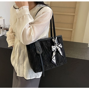 Detail of black pleated tote bag with geometric silk scarf shown on casual outfit