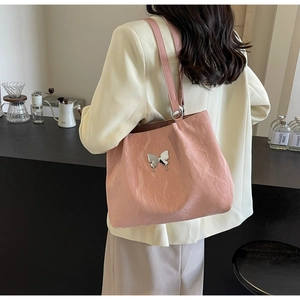 Pink textured tote bag with silver butterfly charm shown in a modern lifestyle setting