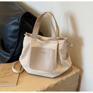 Détail du sac fourre-tout en nylon beige avec poignées en cuir et logo embossé