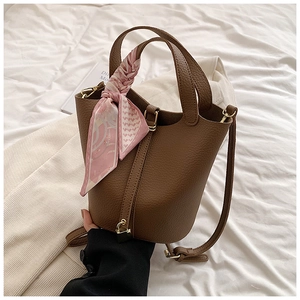 Detailed view of dark brown pebbled leather bucket bag with a pink floral silk scarf handle