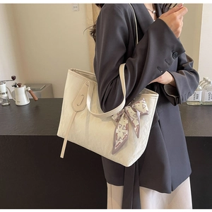 Detail of cream white tote bag with textured finish and silk scarf handle decor