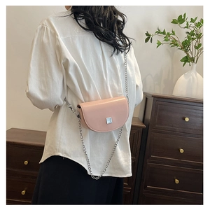 Rear view of a model wearing a pink saddle bag with a silver chain strap on a white shirt