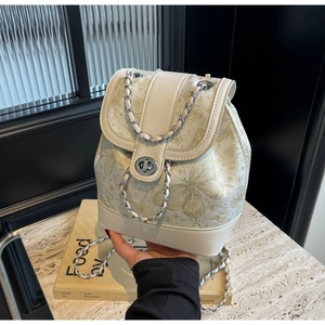 Detail of mini backpack with golden butterfly patterns and chain shoulder strap