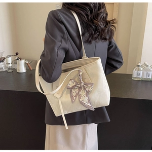 Close-up of cream tote bag with elegant silk scarf wrapped around the handle strap