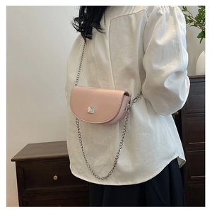 Detailed side view of a pink mini saddle bag with silver chain strap and metal clasp