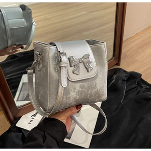 Close-up of silver glitter bucket bag with a metallic bow detail and adjustable strap