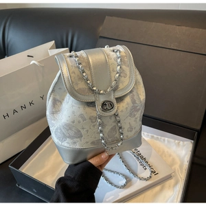 Close-up of silver mini backpack with butterfly prints and metal chain strap in a gift box