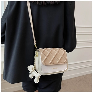 Détail du sac à bandoulière matelassé avec design beige et breloque chiot mignonne