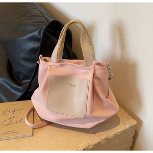 Gros plan détaillé d'un sac cabas en nylon rose avec poche en cuir sur socle en pierre