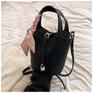 Detail of black pebbled leather bucket bag with silk scarf handle and golden padlock