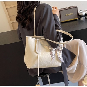 Detailed view of white pleated tote bag with a fashion silk scarf handle on a shoulder strap