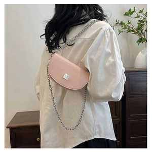 Pink semi-circular mini saddle bag with silver chain strap shown in a lifestyle setting