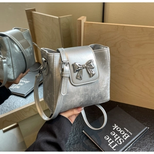 Close-up of a silver bucket bag featuring a 3D metallic bow and elegant matte finish