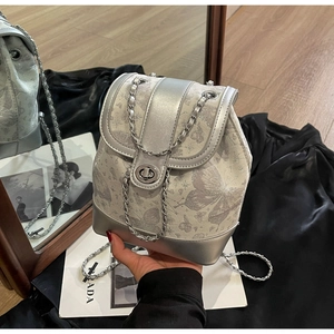 Detailed close-up of a silver butterfly print mini backpack with chain strap and twist lock