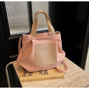 Gros plan du sac cabas en nylon rose montrant l'écusson de la marque et les anses en tissu
