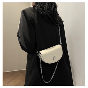 Detailed view of white saddle bag with silver chain strap on black blazer outfit