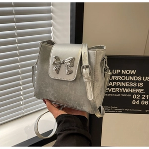 Detailed shot of silver-grey mini bucket bag with metallic bow and adjustable leather strap
