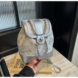 Detail of silver drawstring backpack featuring butterfly jacquard and metal chain strap