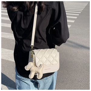 Photo de rue d'un sac bandoulière beige matelassé avec un charmant pendentif en chien