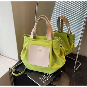 Détail du fourre-tout en nylon vert avec poche en cuir et logo de marque embossé