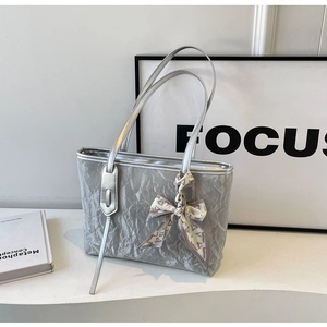 Detail of silver tote bag featuring pleated texture and a decorative fashion scarf bow