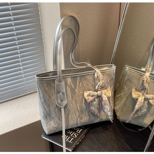 Detail view of silver tote bag with metallic crinkle texture and fashion silk scarf handle