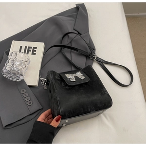 Detail of black suede bucket bag with silver bow on a blazer in a cozy lifestyle setting