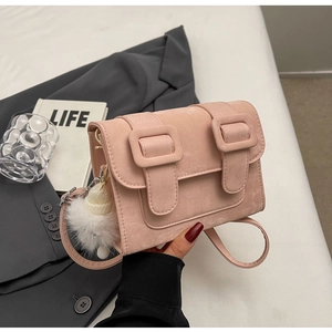Detail of pink matte PU leather crossbody bag with double buckles and white plush charm