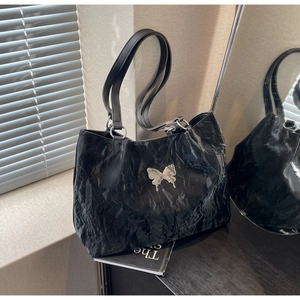 Detailed view of black tote bag featuring a silver butterfly charm and crinkle texture