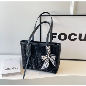 Close-up of black pleated tote bag with decorative black and white silk scarf detail
