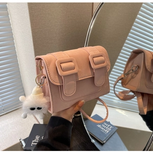 Detail of pink matte Cambridge bag with dual buckles and a cute plush doll charm