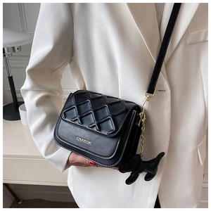 Détail d'un sac à bandoulière noir avec texture matelassée et charm chien mignon