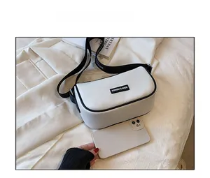 Detail of white bow bag showing size comparison with a smartphone and crossbody strap