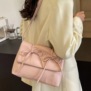 Sac à bandoulière rose plissé avec nœuds décoratifs porté par un mannequin