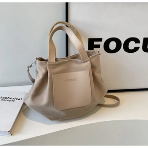 Détail du sac cabas en nylon beige avec poche en cuir, poignées et bandoulière amovible
